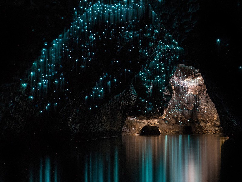 A dark cave filled with water and twinkling lights coming from the ceiling.