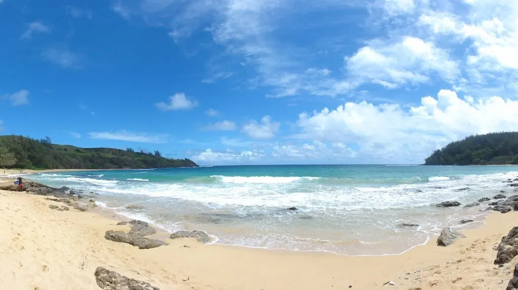 Kauai beach with waves and mountains.