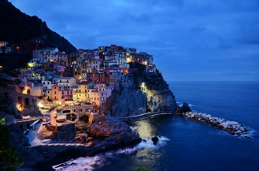 An Italian village at night on a cliff overlooking the ocean.