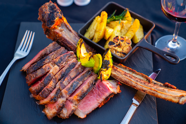 Plate of ribs with slices of grilled vegetables.