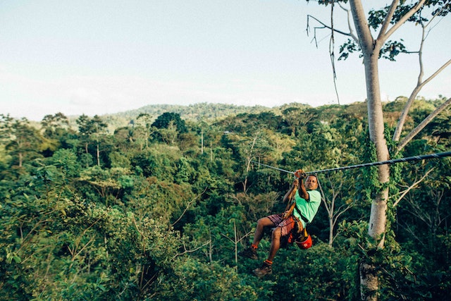 Person on a zipline over brilliant green rainforest.