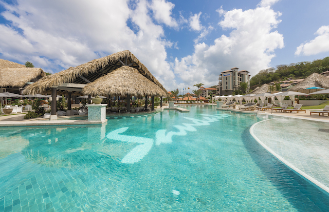 A pool at a sandals resort with a swim up bar.