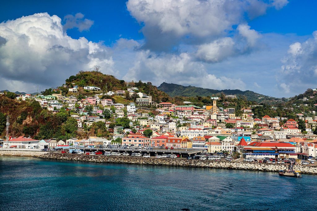 Grenada coastline with colorful buildings and mountains in the distance.