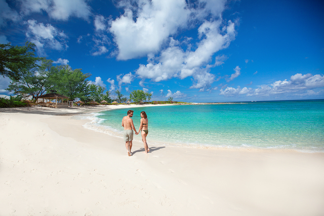 Two people standing on a sandy beach.