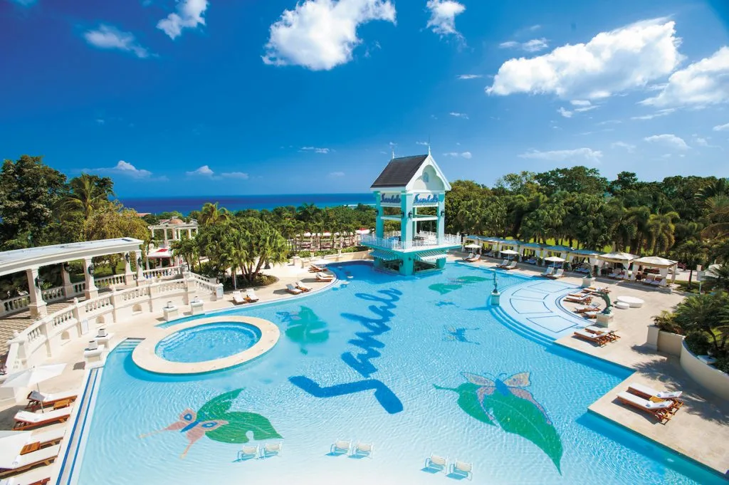 A pool at Sandals Ochi Beach resort surrounded by trees.