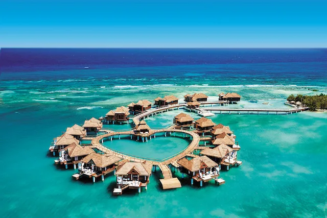 Overwater bungalows organized in the shape of a heart over sparkling, clear water.