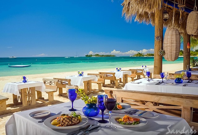 Beachside dining with set tables, white tablecloths and blue water glasses.
