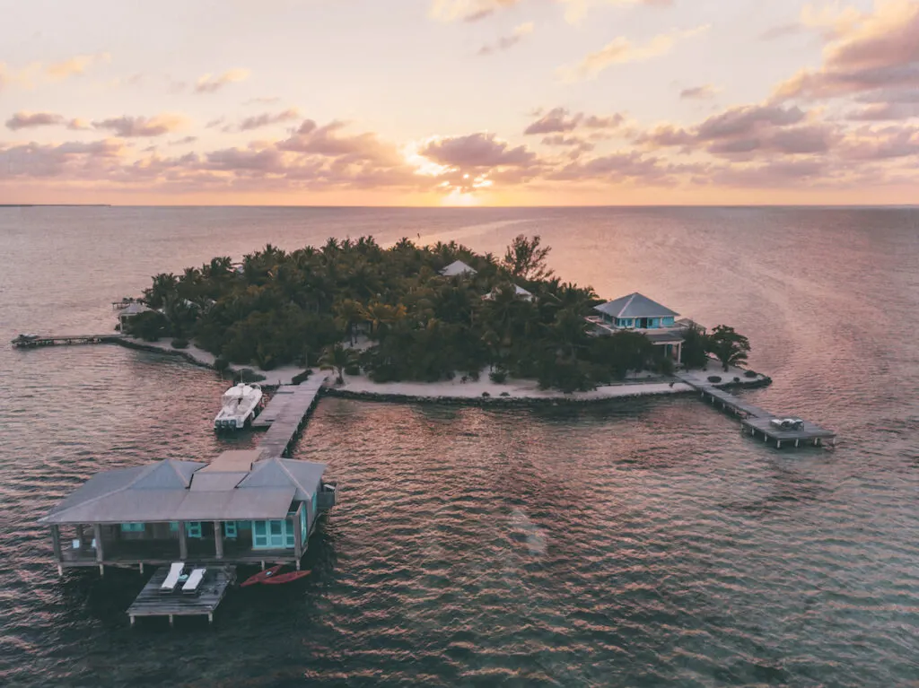 Small island with docks and overwater bungalows during a sunset.