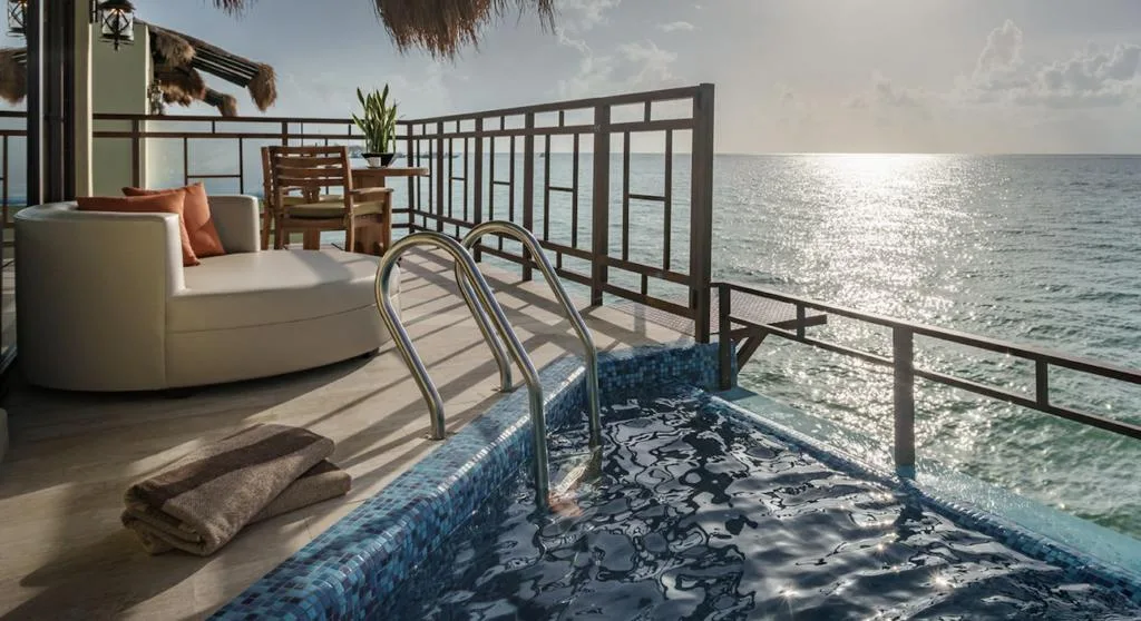 A plush lounge chair overlooking a pool and the ocean.