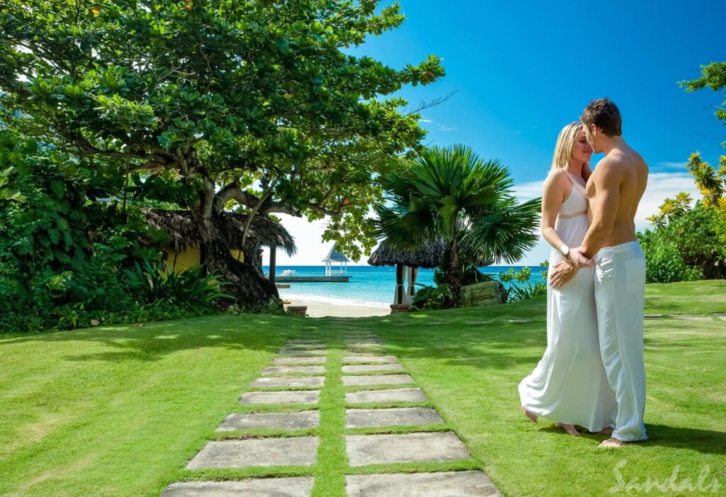 Sandals Royal Plantation - a romantic couple is hugging on the grass leading up to the beach