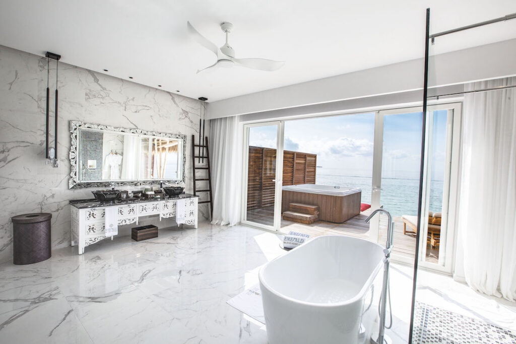 An elegant resort bathroom with marble title, a stand-alone soaker tub all overlooking the ocean.