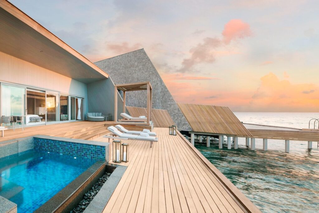 A pool and deck outside a resort suite overlooking a dock and the ocean.