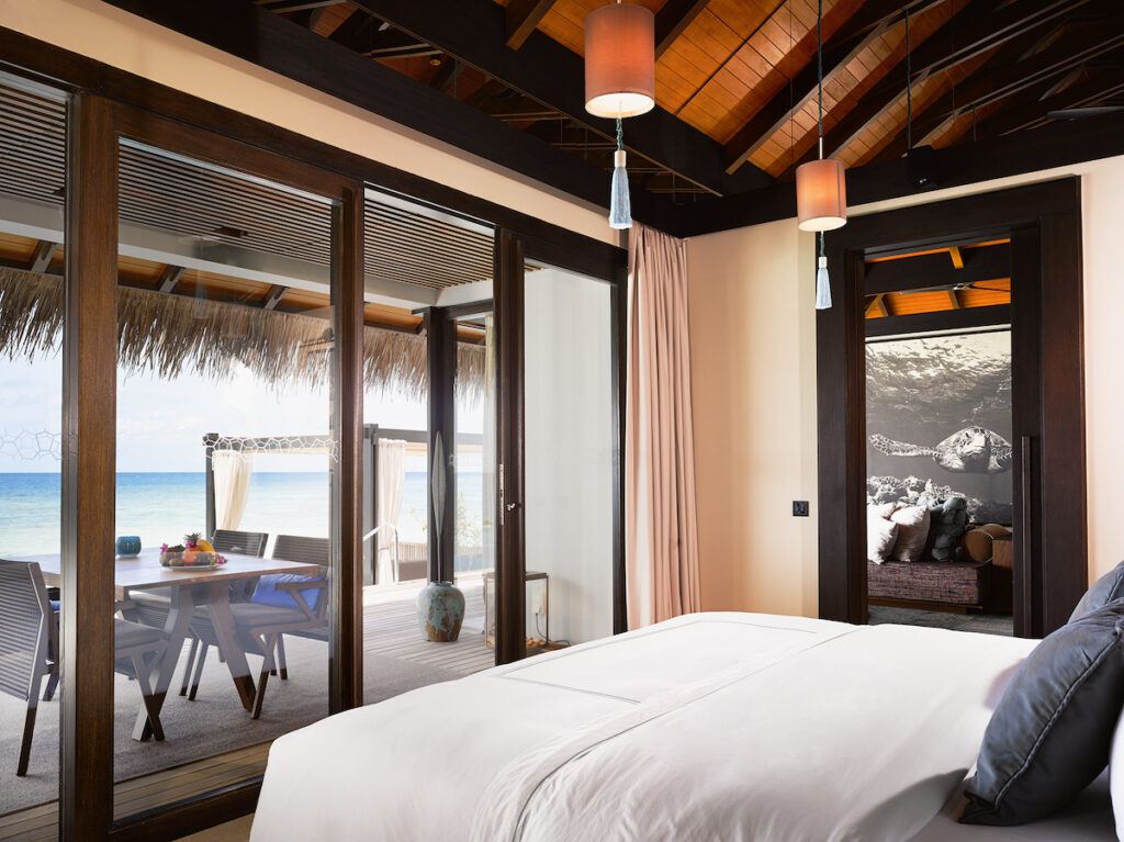 A bedroom with glass doors overlooking a private lounge bed and the ocean.