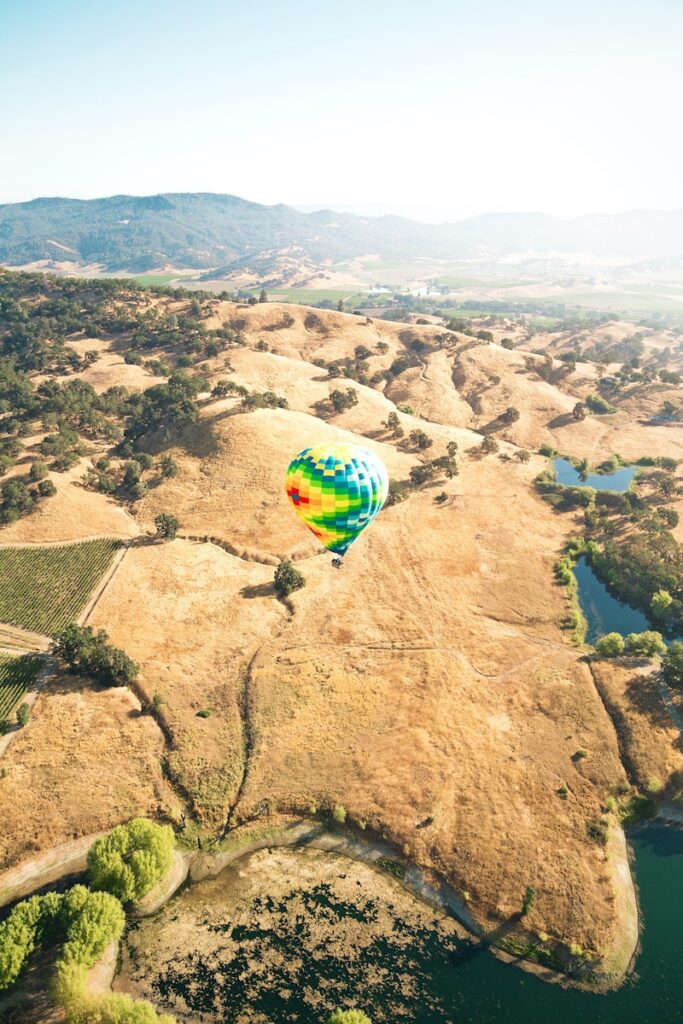 Arial view of Napa Valley with a colorful hot air balloon in the middle.