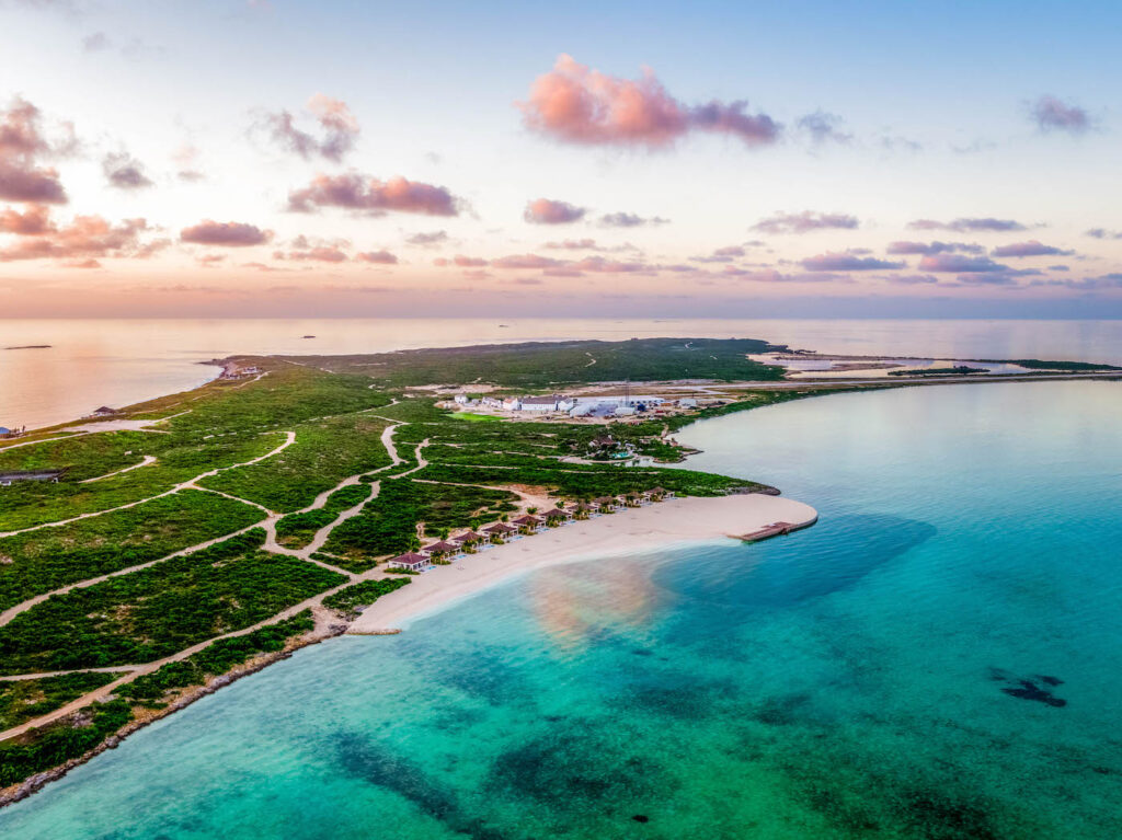 Arial view of an island with bungalows and villas on the beach.