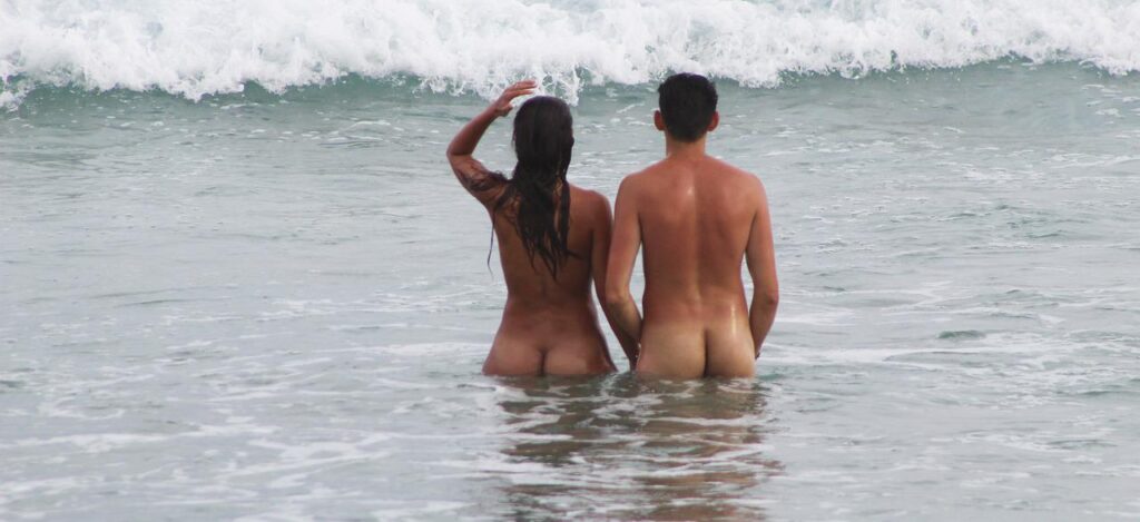 couple in the water at a clothing optional beach