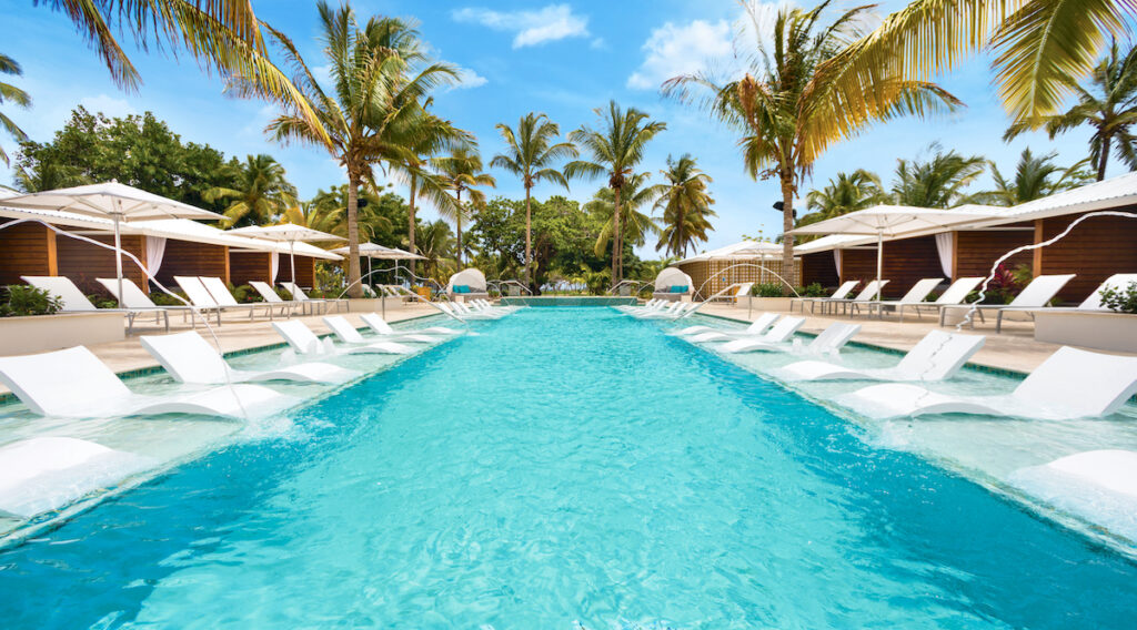 A view of the pool at Serenity at Coconut Bay surrounded by lounge chairs and umbrella.