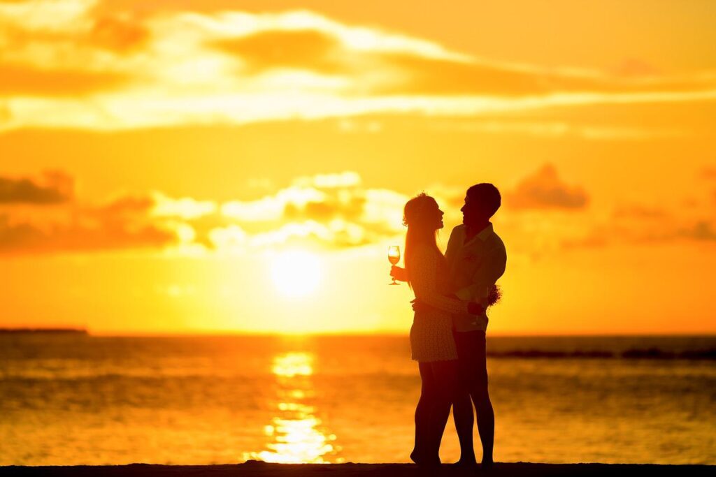 Silhouette of a couple on a beach at sunset.