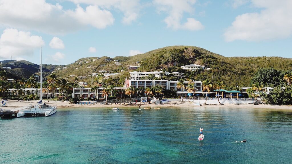 A seaside resort with a boat docked and people kayaking and swimming in the foreground.