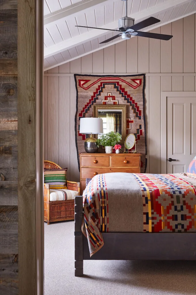 A look into a bedroom with vaulted ceilings and a bed with lots of southwestern style decorations and colors.