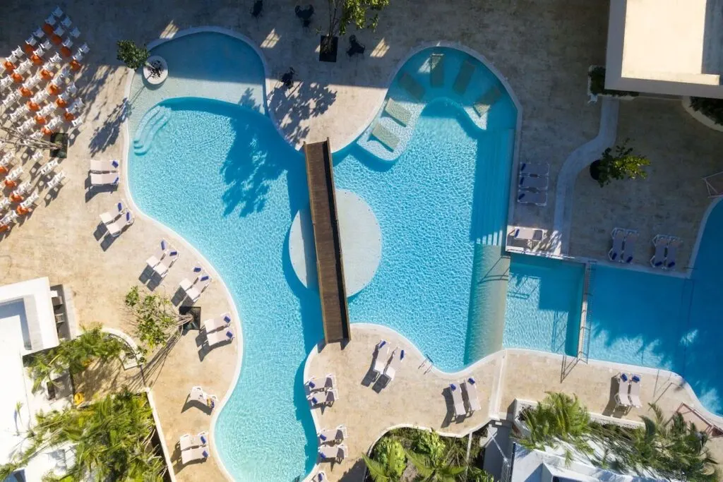 An aerial view of a pool at Emotions Juan Dolio in the Dominican Republic surrounded by lounge chairs.
