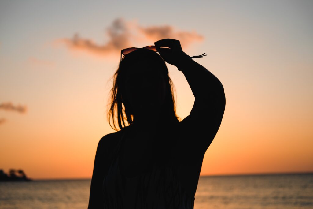 Silhouette of a woman looking at the ocean as sunset.