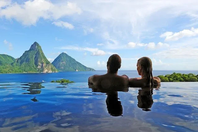 A couple in an edgeless pool looking at the ocean and mountains.