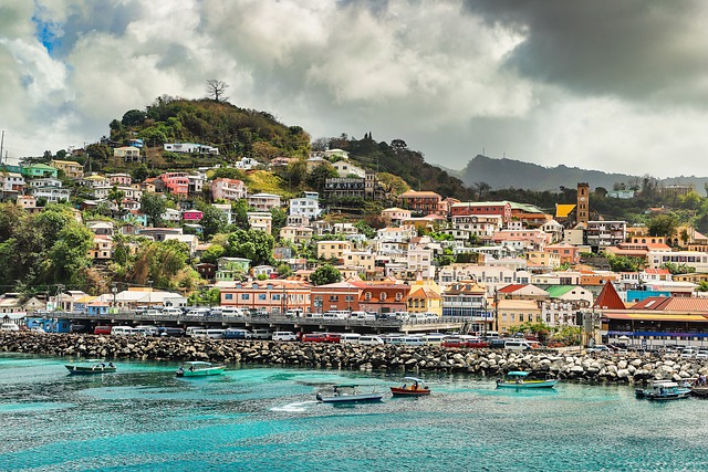 Grenada coastline with boats in the water and a mountain in the distance filled with multicolor homes.